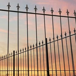 Low angle view of fence against sky during sunset