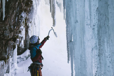 Female ice climber holding equipment