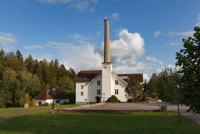 Houses on field by building against sky