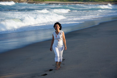 Portrait smiling mid adult woman walking on sandy beach