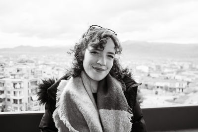 Portrait of young woman standing against buildings