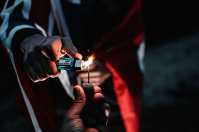 Close-up of friends lighting firework at night