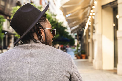 Rear view of man wearing hat sitting in city