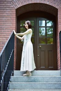 Portrait of young woman standing against brick wall