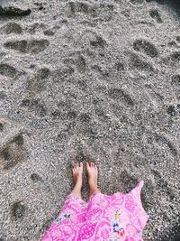 Low section of woman standing on sand