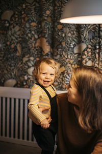 Mother embracing smiling son at home