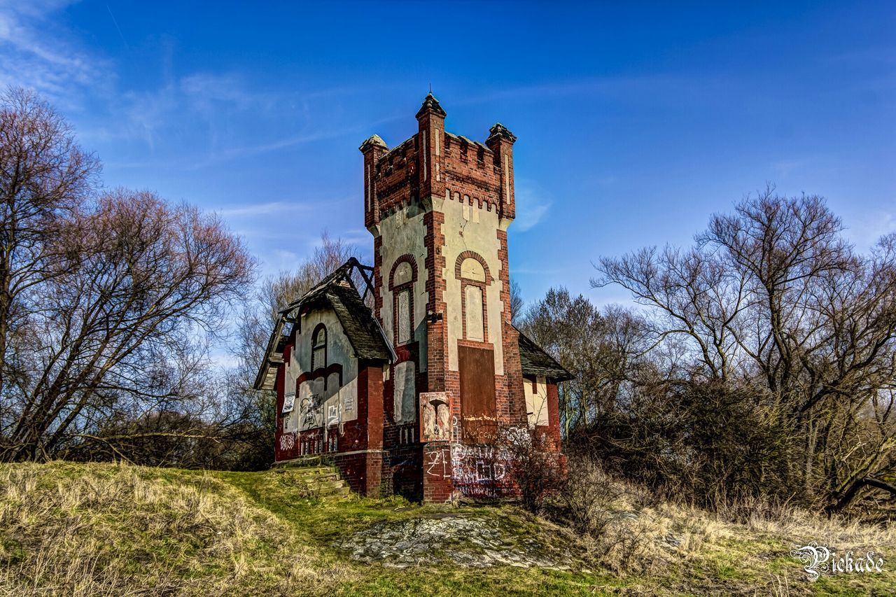 architecture, built structure, tree, sky, building exterior, religion, grass, church, place of worship, spirituality, blue, low angle view, field, cloud - sky, cloud, day, cross, history