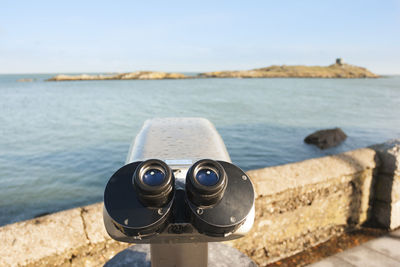 Close-up of coin-operated binoculars at beach against sky