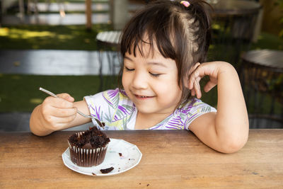 Close-up of cute girl eating cupcake on table