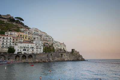 Buildings by sea against clear sky