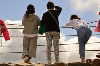 Rear view of people walking on railing