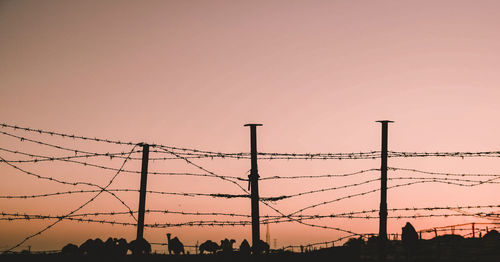 Low angle view of silhouette fence against sky during sunset