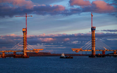 Cranes at commercial dock against sky