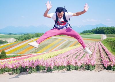 Woman jumping on field against sky