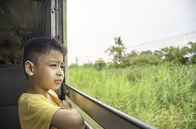 Boy looking through window of bus