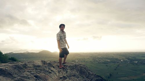 Full length of man standing on mountain against sky during sunset