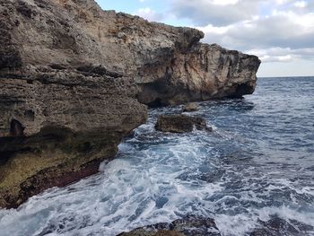 Rock formation in sea against sky