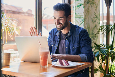 Portrait of young man using mobile phone in restaurant