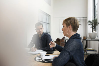 Business professional discussing with colleague during meeting at table