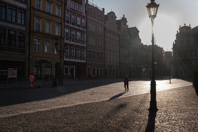 Woman walking on street amidst buildings in city