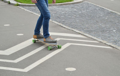 Low section of man skateboarding on road