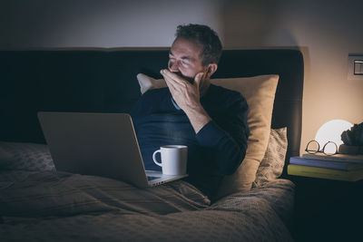 Tired man sleeping on bed after hard works with laptop until late at night. bored boy in bedroom