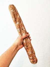 Close-up of hand holding bread against white background