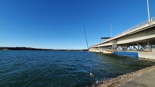 Bridge over sea against clear blue sky