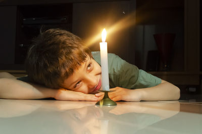 Child looking at a lit candle lying on the floor of the house. salvador, bahia, brazil.
