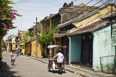 Rear view of market vendor on street by old buildings