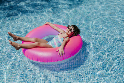 High angle portrait of smiling relaxing on inflatable ring in swimming pool