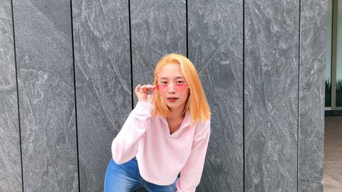 Portrait of woman standing against wooden wall