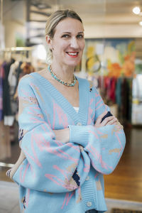 Smiling female entrepreneur with arms crossed standing outside clothing store