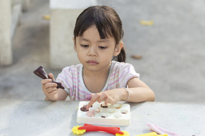 Close-up of cute girl playing with childs play clay at table outdoors