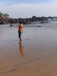 Rear view of boy on beach against sky