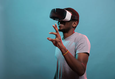 Young man wearing vr headset against blue background