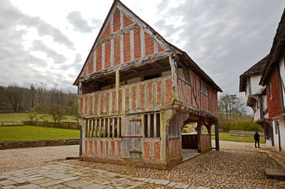 Houses on field by buildings against sky