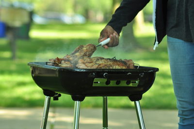 Close-up of man preparing food on barbecue grill