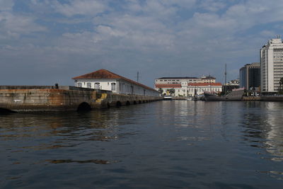 Scenic view of river by buildings against sky