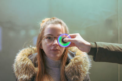 Cropped hand holding illuminated fidget spinner by young woman