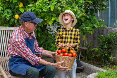 Portrait of smiling friends with fruits at farm