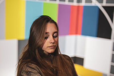 Young woman looking down against wall