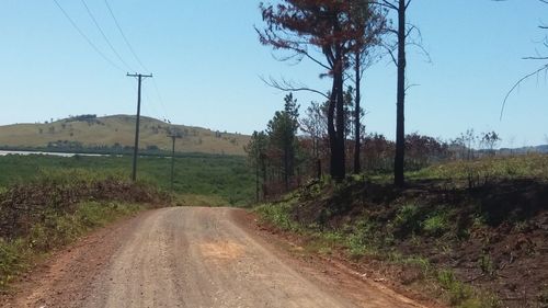 Road amidst field against clear sky