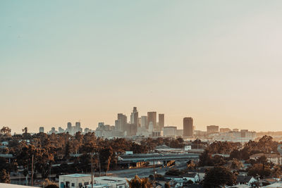 Modern buildings in city against clear sky during sunset