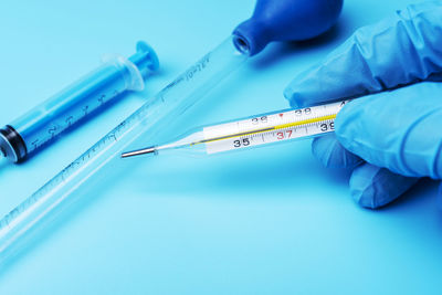 Close-up of hand holding blue over white background