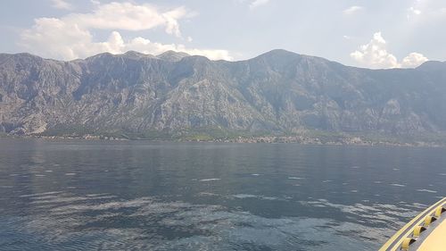 Scenic view of sea by mountains against sky