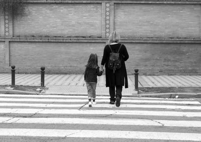 Rear view of mother and daughter crossing road