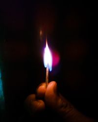 Close-up of hand holding illuminated candle