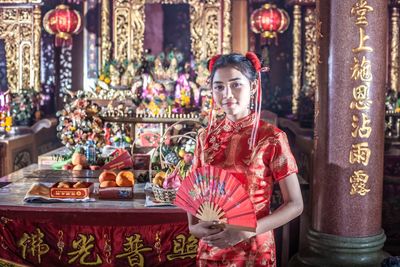 Portrait of teenager holding hand fan standing at temple