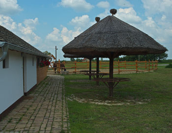 Gazebo on footpath amidst buildings against sky